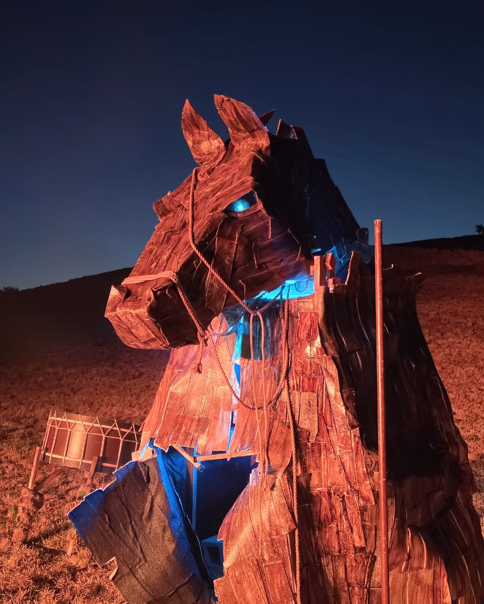 Caballo de Troya gigante de tablas de madera iluminado de noche con luces rojas y azules